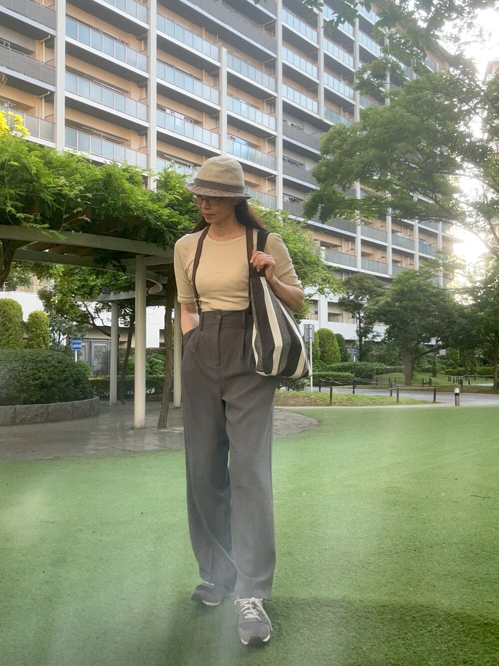 グレー系のスニーカー、グレー系のスラックス、ベージュ系のTシャツ/カットソーを着用したレディースの夏コーディネートの2枚目の写真