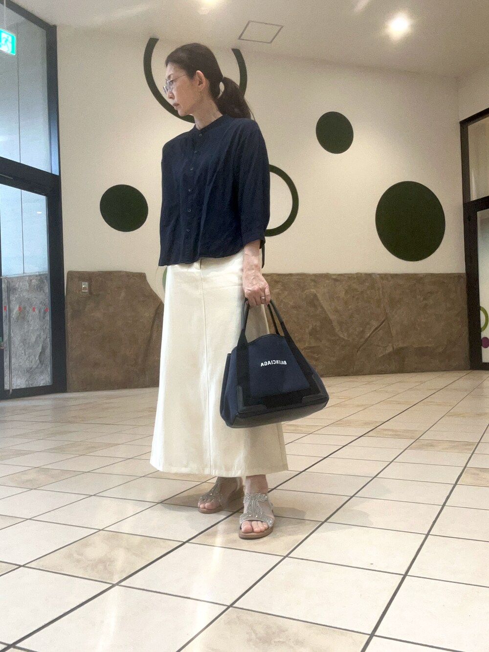 ブルー系のシャツ/ブラウス、ホワイト系のスカート、ゴールド系のサンダルを着用したレディースの春コーディネートの2枚目の写真