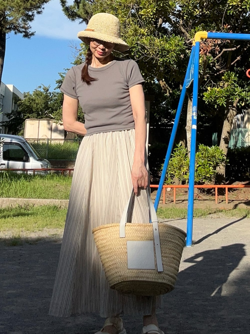 グリーン系のTシャツ/カットソー、ベージュ系のスカート、ホワイト系のかごバッグを着用したレディースの夏コーディネートの2枚目の写真