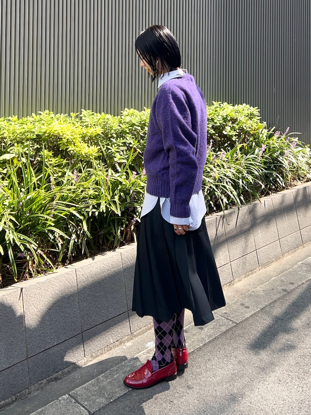 パープル系のニット/セーター、ブルー系のシャツ/ブラウス、ブラック系のスカートを着用したレディースの秋コーディネートの2枚目の写真