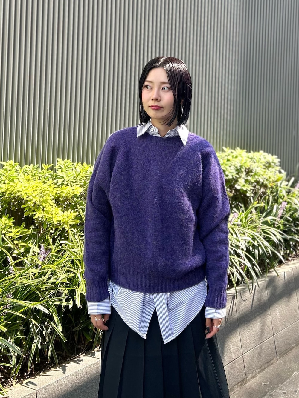 パープル系のニット/セーター、ブルー系のシャツ/ブラウス、ブラック系のスカートを着用したレディースの秋コーディネートの3枚目の写真