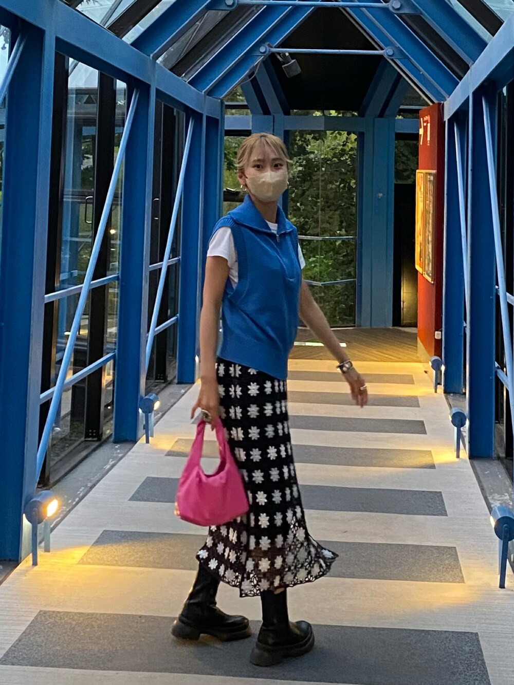 ブルー系のベスト、ブラック系のワンピース、ピンク系のトートバッグを着用したレディースの秋コーディネートの2枚目の写真