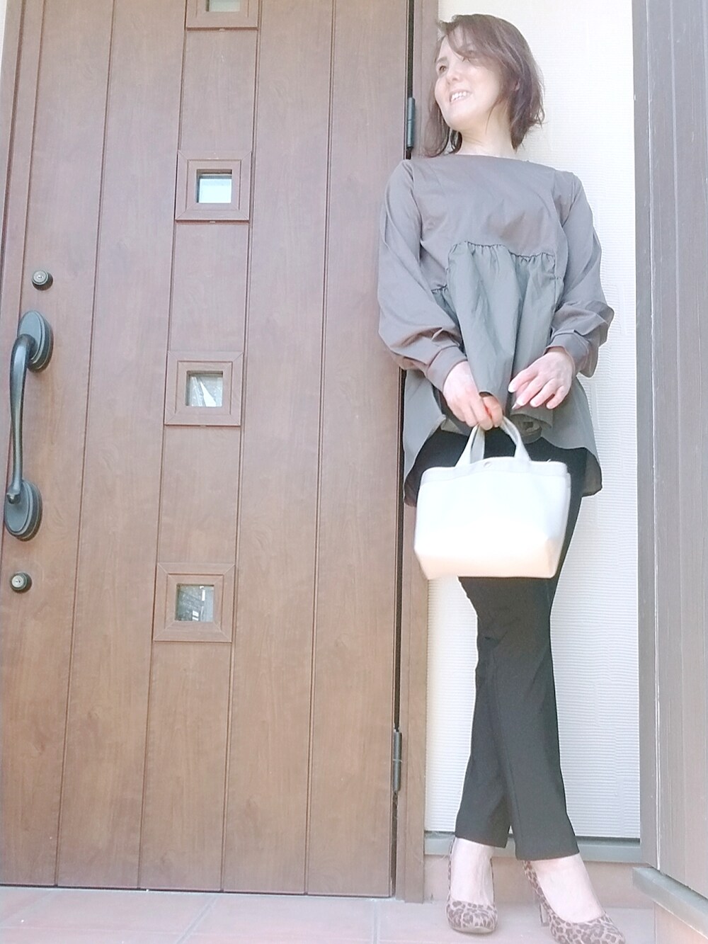 ベージュ系のトートバッグ、ブラック系のパンツ、ブラック系のTシャツ/カットソーを着用したレディースの夏コーディネートの2枚目の写真