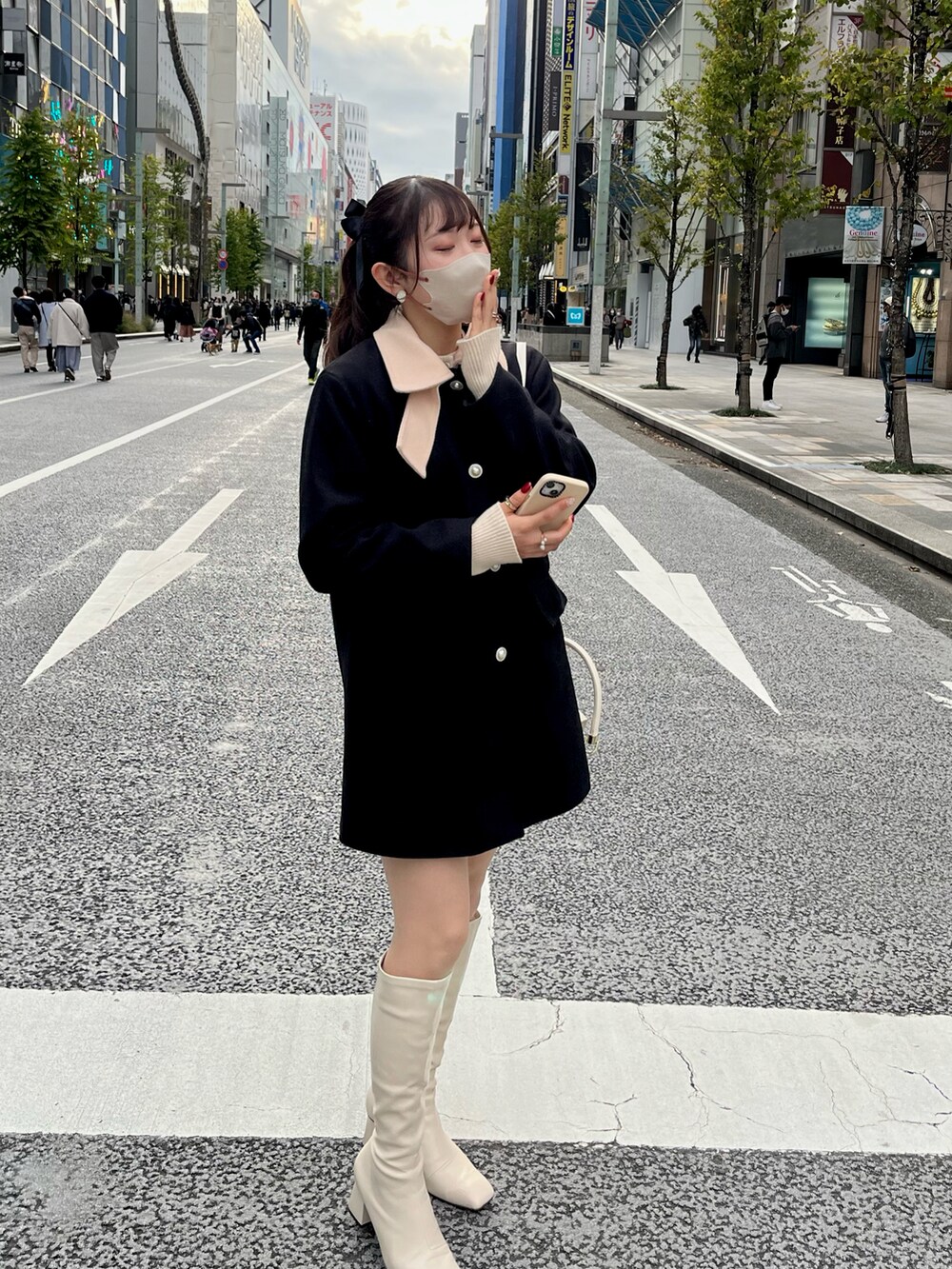 ブラック系のジャケット/アウター、ホワイト系のブーツ、ホワイト系のハンドバッグを着用したレディースの冬コーディネートの2枚目の写真