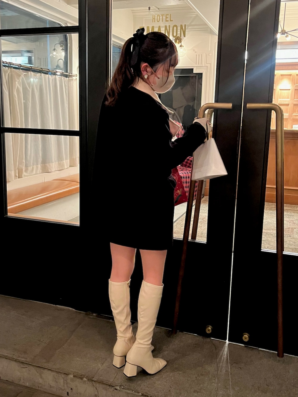 ブラック系のジャケット/アウター、ホワイト系のブーツ、ホワイト系のハンドバッグを着用したレディースの冬コーディネートの3枚目の写真