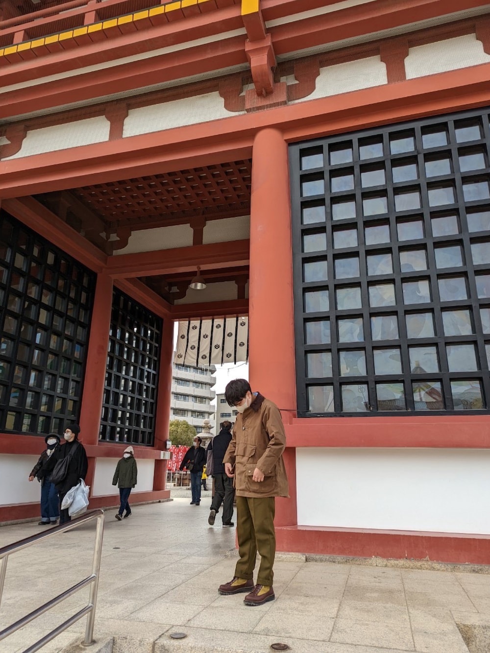 グリーン系のパンツ、ブルー系のショルダーバッグ、ブラウン系のジャケット/アウターを着用したメンズの冬コーディネートの2枚目の写真