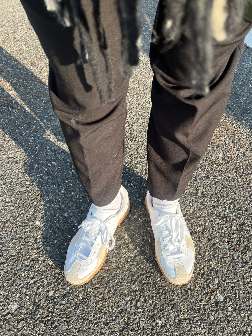 ホワイト系のスニーカー、ブラック系のニット/セーター、ブラック系のマフラーを着用したレディースの冬コーディネートの2枚目の写真