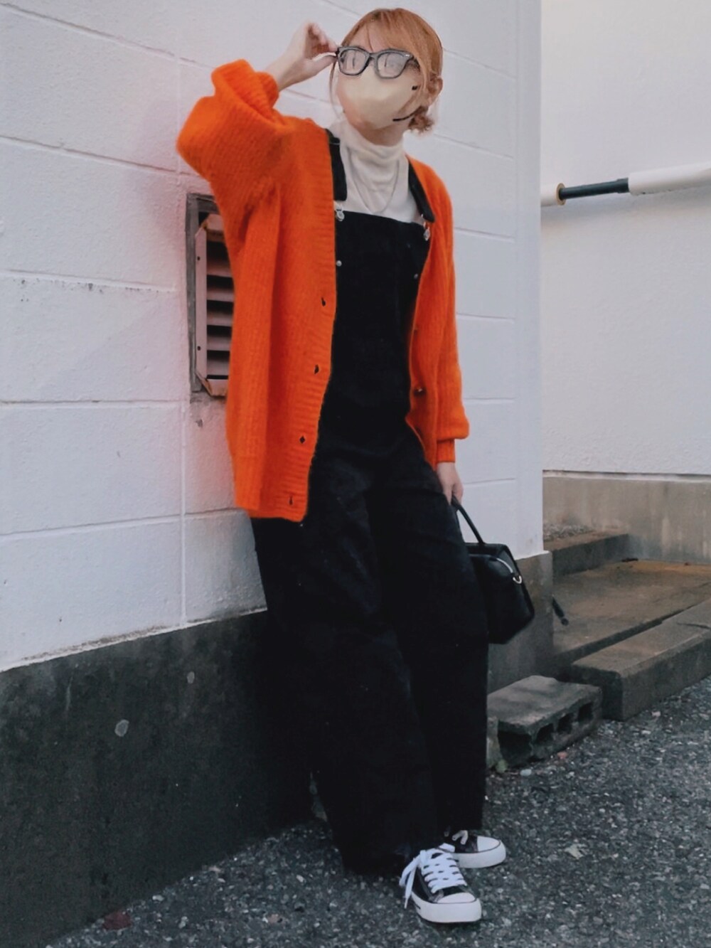 オレンジ系のカーディガン/ボレロ、ホワイト系のTシャツ/カットソー、ブラック系のサロペット/オーバーオールを着用したレディースの秋コーディネートの2枚目の写真