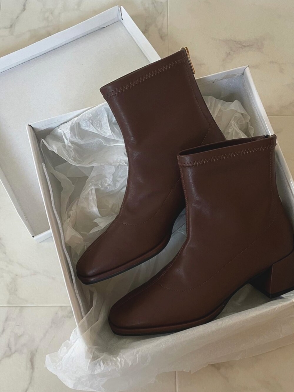 オレンジ系のニット/セーター、ブルー系のデニムスカート、ブラウン系のブーツを着用したレディースの秋コーディネートの2枚目の写真