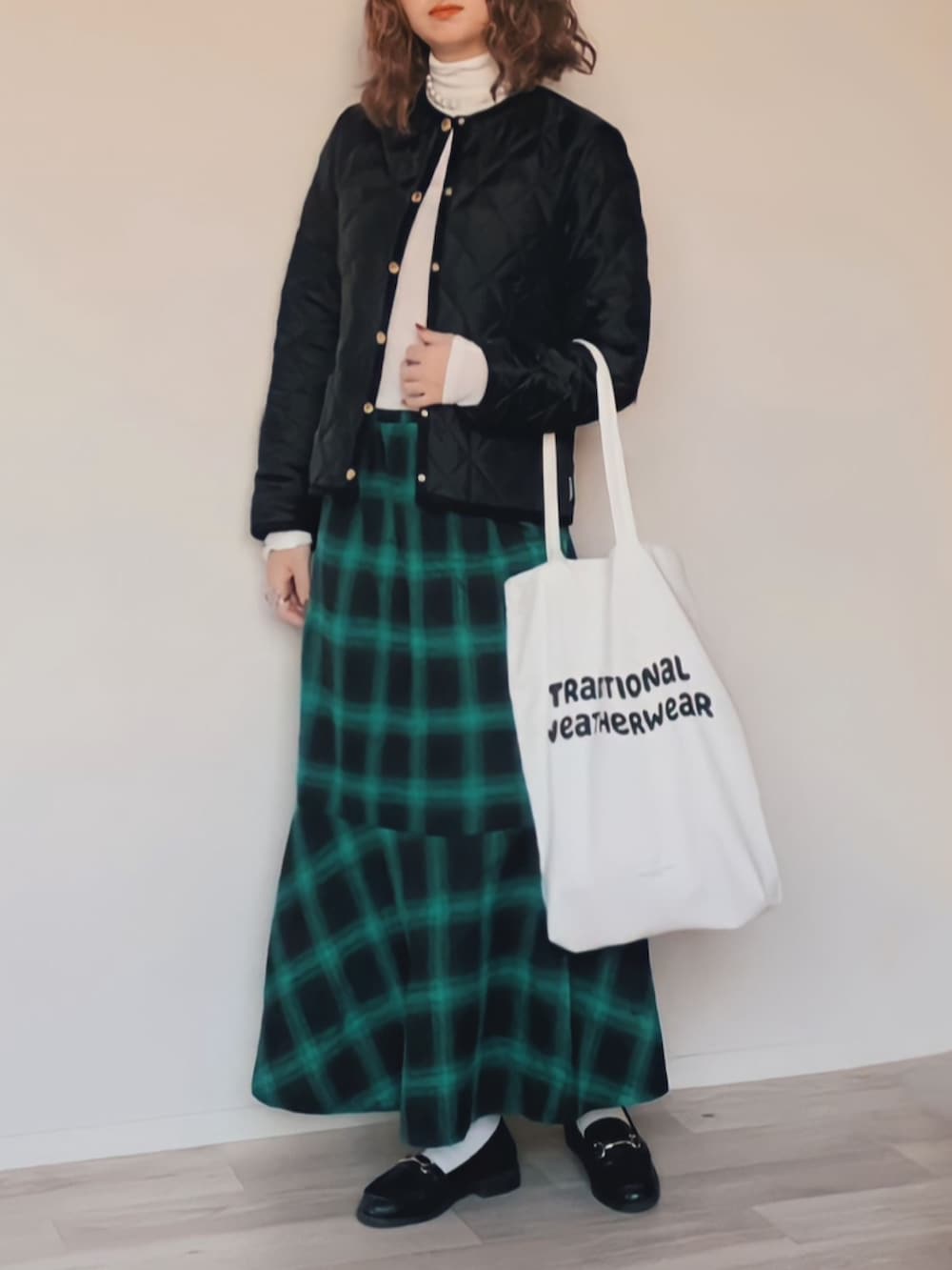 ブラック系のノーカラージャケット、ホワイト系のTシャツ/カットソー、グリーン系のスカートを着用したレディースの秋コーディネートの2枚目の写真