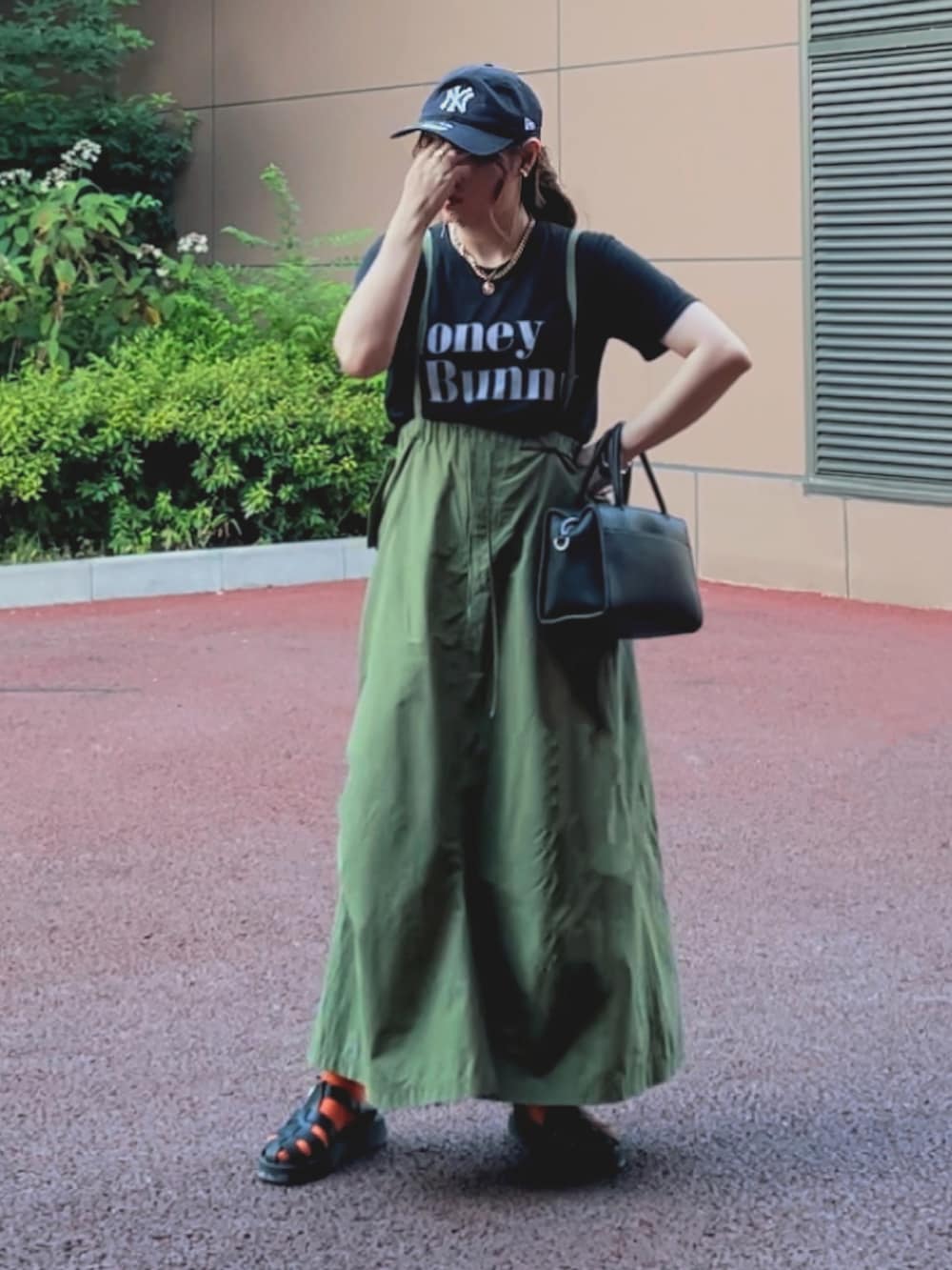 ブラック系のTシャツ/カットソー、グリーン系のスカート、ブラック系のサンダルを着用したレディースの夏コーディネートの2枚目の写真