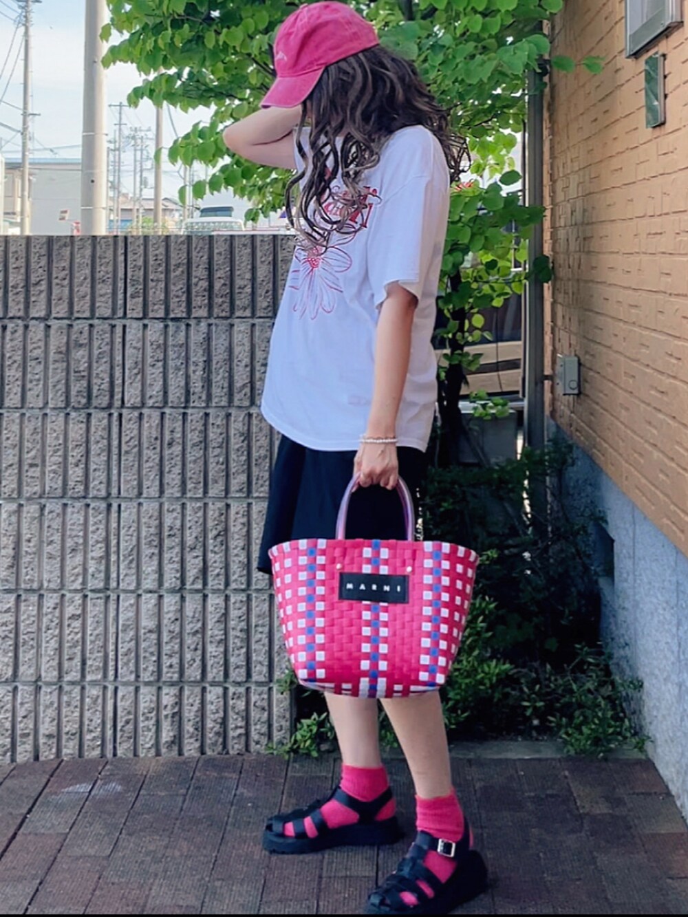 ホワイト系のTシャツ/カットソー、ブラック系のパンツ、ブラック系のサンダルを着用したレディースの夏コーディネートの2枚目の写真