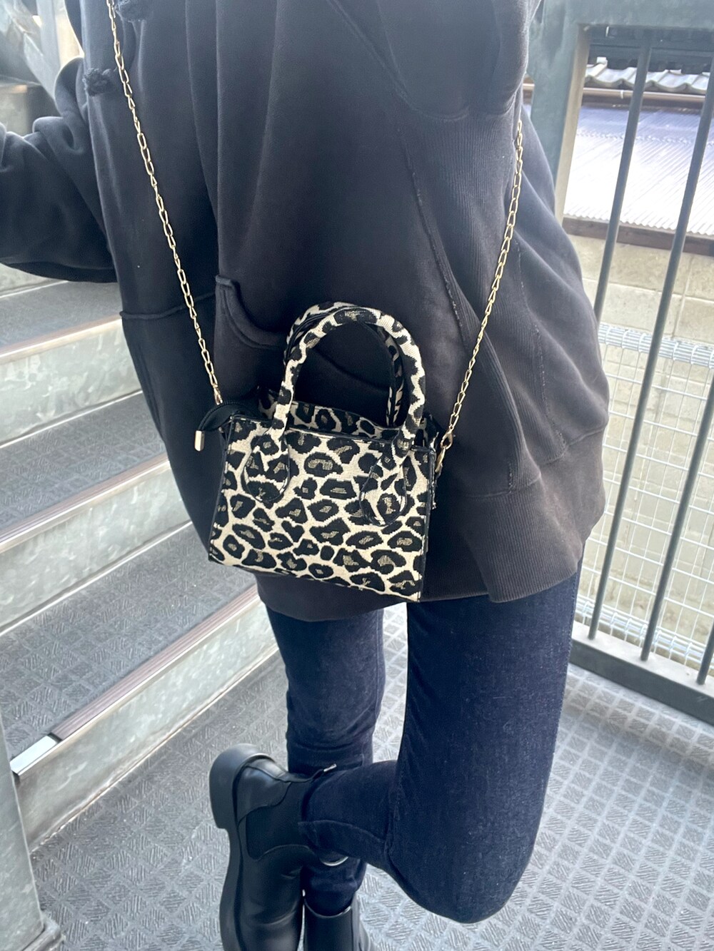 ブラック系のパーカー、ブラック系のブーツ、ブルー系のデニムパンツを着用したレディースの春コーディネートの3枚目の写真