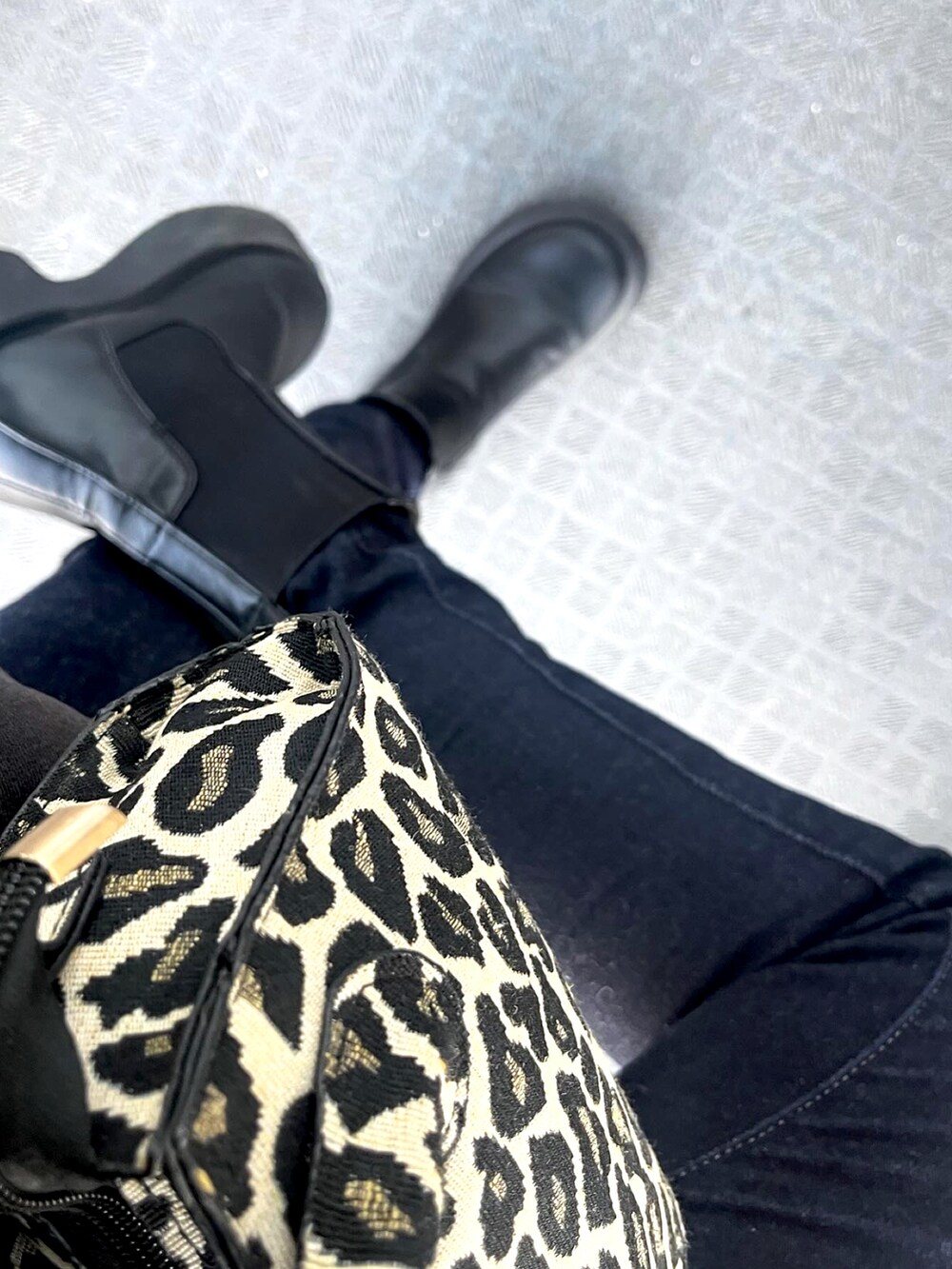 ブラック系のパーカー、ブラック系のブーツ、ブルー系のデニムパンツを着用したレディースの春コーディネートの2枚目の写真