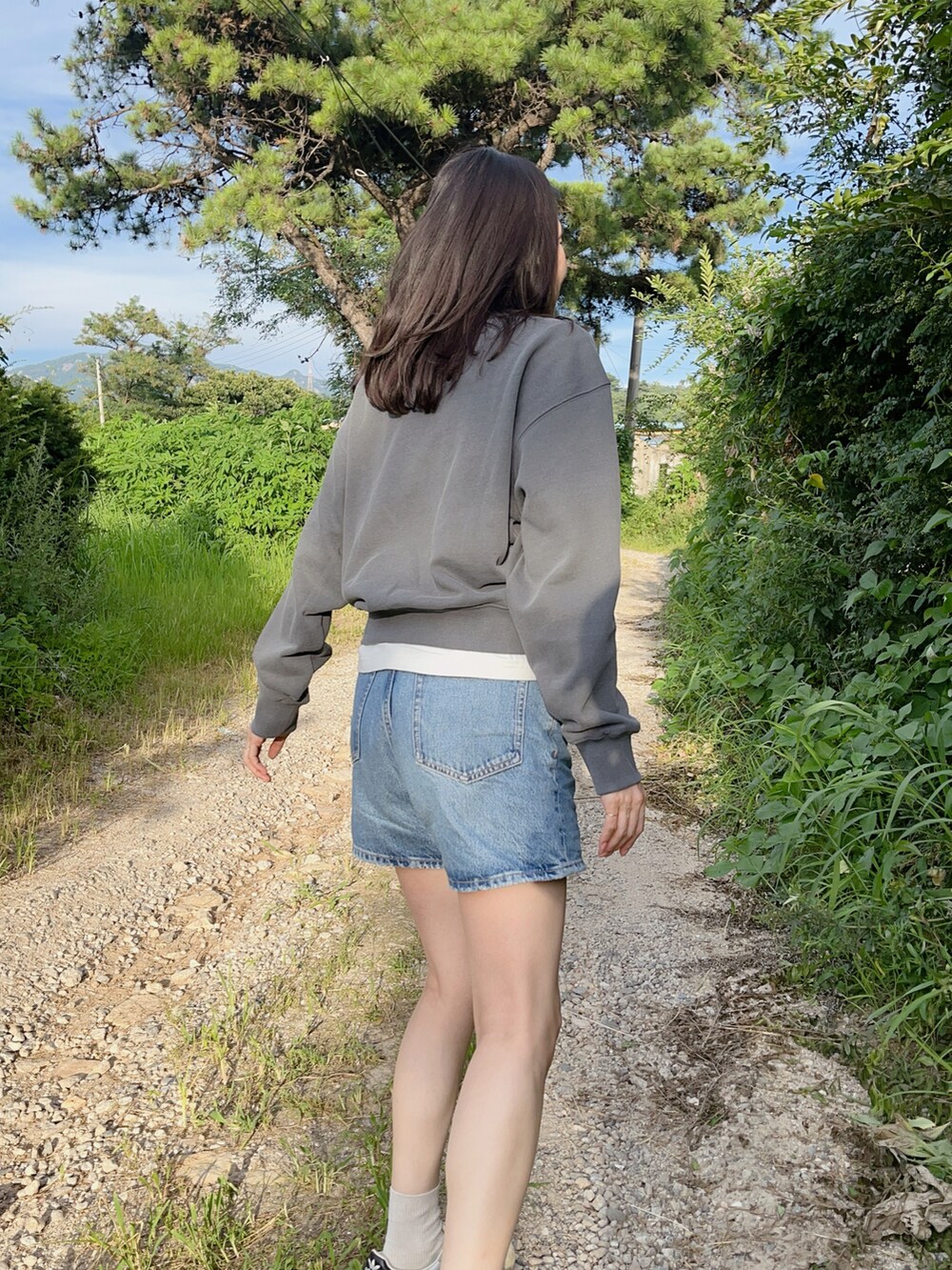 ブルー系のパンツ、グレー系のトップス、ホワイト系のスニーカーを着用したレディースの夏コーディネートの3枚目の写真