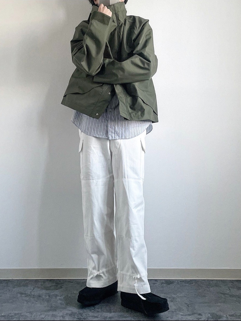 グリーン系のマウンテンパーカー、ホワイト系のカーゴパンツ、ブラック系のモカシン/デッキシューズを着用したメンズの冬コーディネートの2枚目の写真