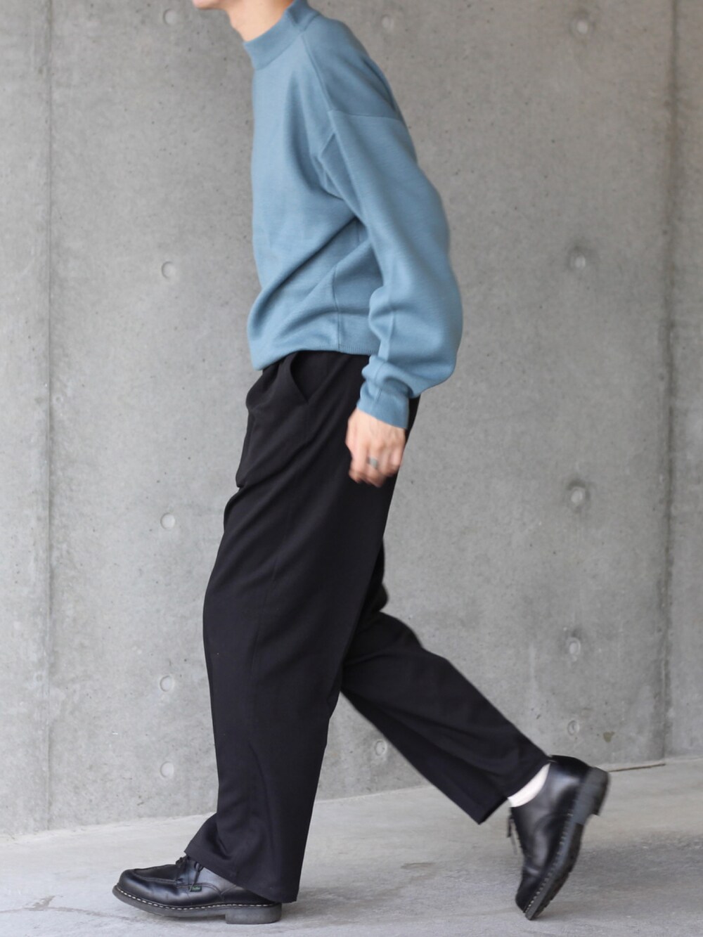 ブルー系のニット/セーター、ブラック系のスラックス、ブラック系のドレスシューズを着用したメンズの秋コーディネートの2枚目の写真