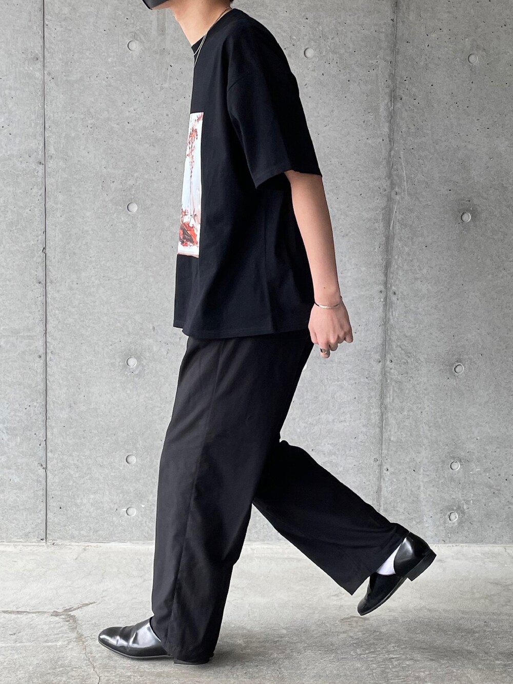 ブラック系のTシャツ/カットソー、ブラック系のスラックス、ブラック系のスリッポンを着用したメンズの夏コーディネートの3枚目の写真