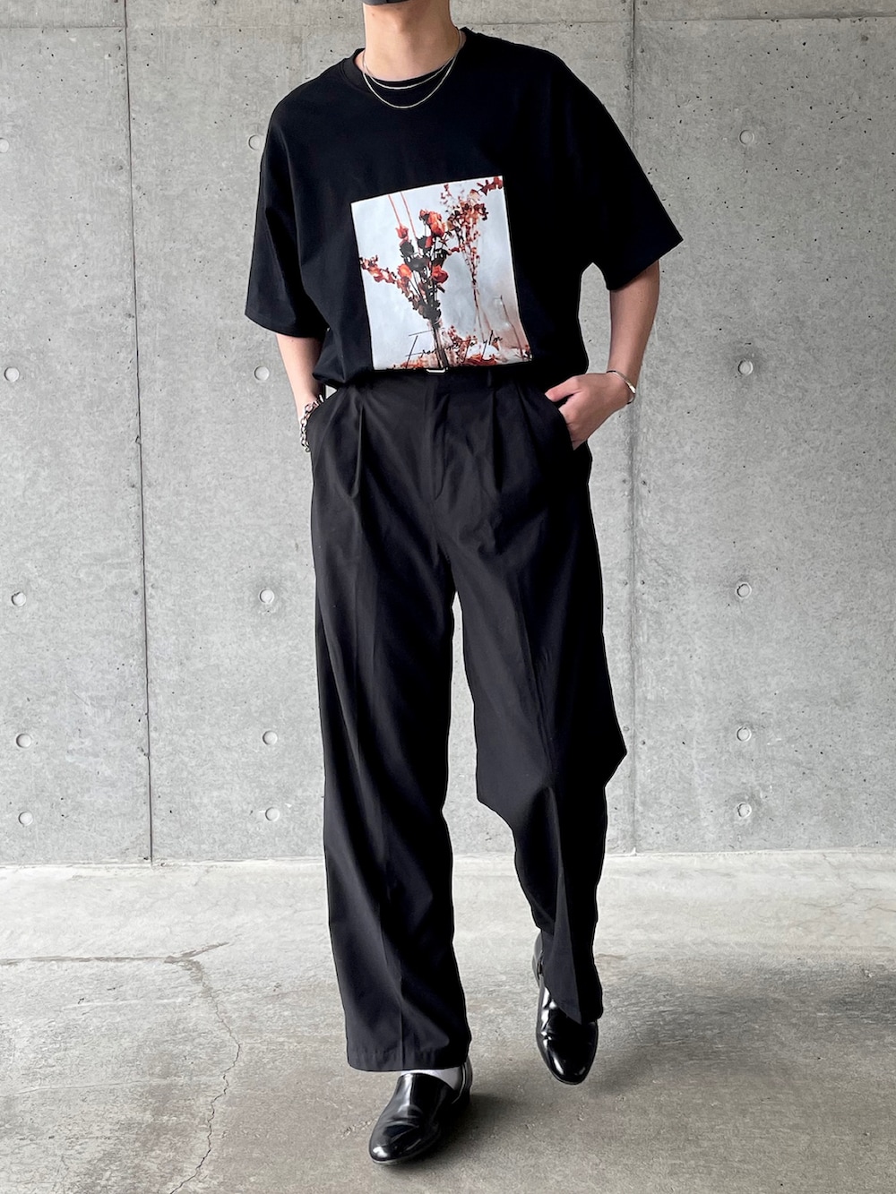 ブラック系のTシャツ/カットソー、ブラック系のスラックス、ブラック系のスリッポンを着用したメンズの夏コーディネートの2枚目の写真