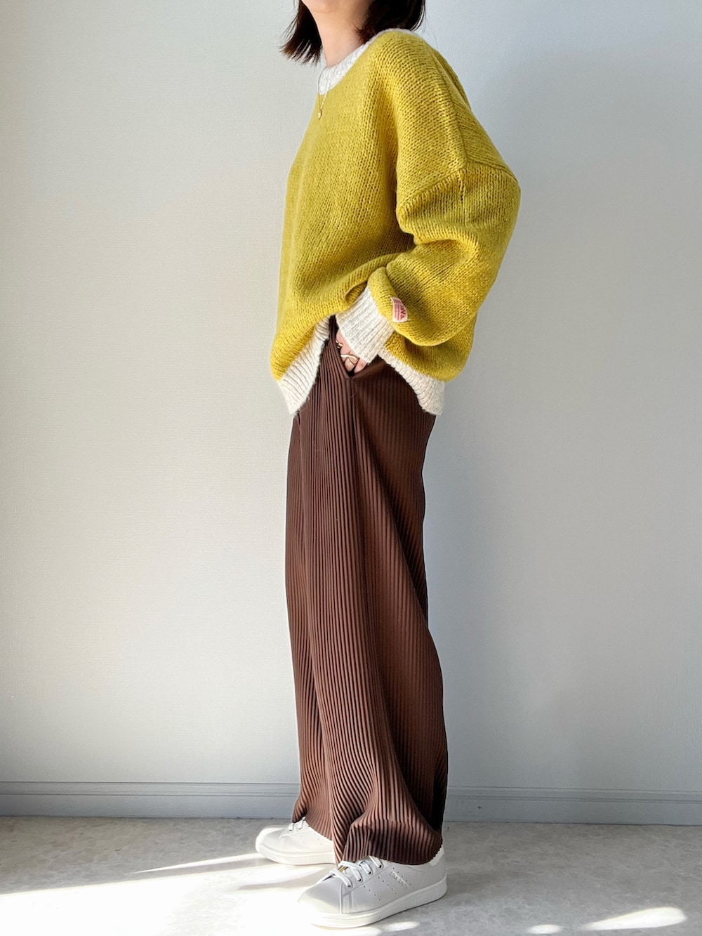 ブラウン系のその他パンツ、ベージュ系のスニーカー、イエロー系のニット/セーターを着用したレディースの秋コーディネートの2枚目の写真