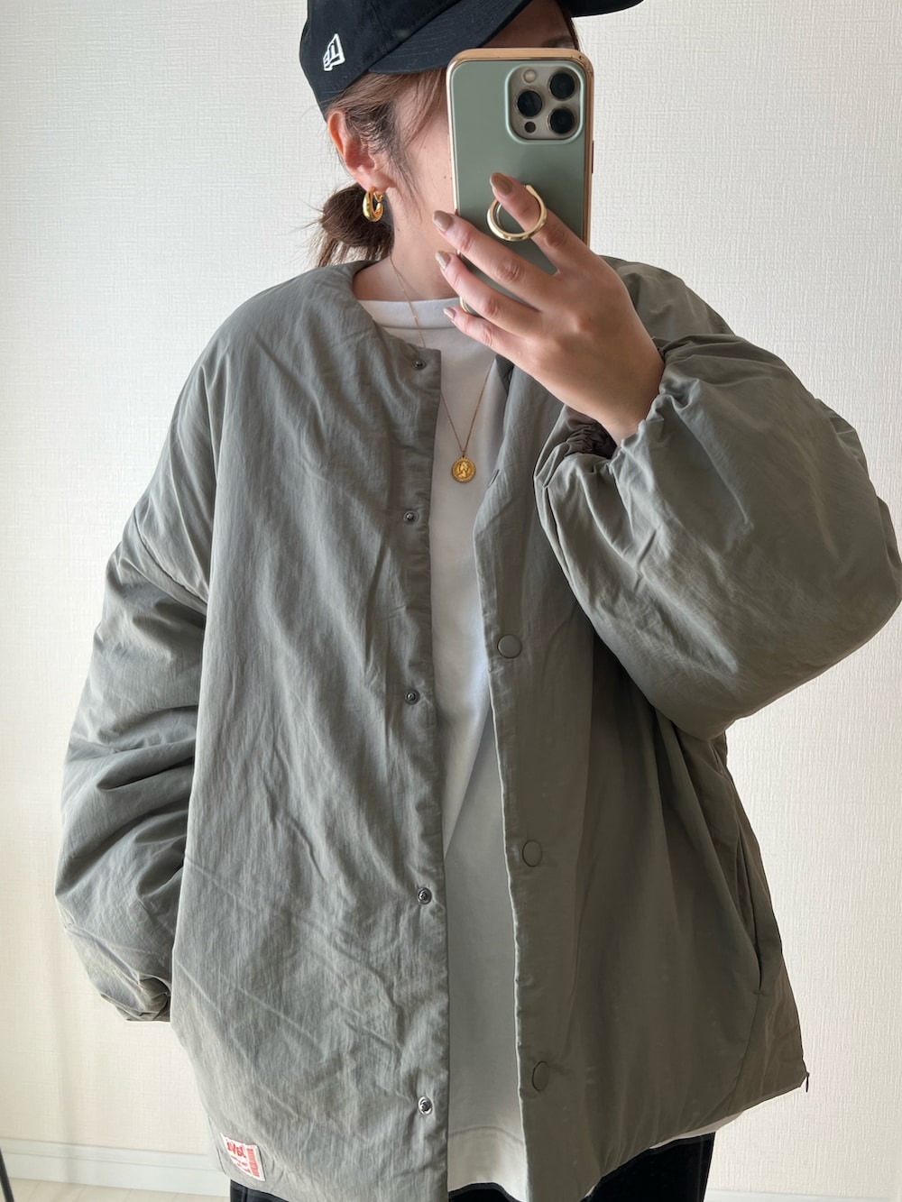 グリーン系のノーカラージャケット、ブラック系のパンツ、ホワイト系のスニーカーを着用したレディースの秋コーディネートの2枚目の写真