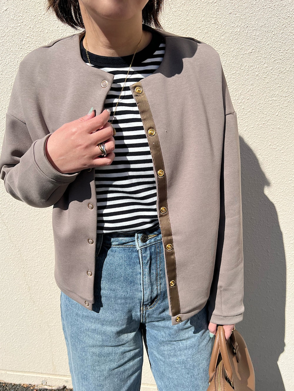 ブルー系のデニムパンツ、ホワイト系のスニーカー、ブラウン系のトップスを着用したレディースの春コーディネートの2枚目の写真