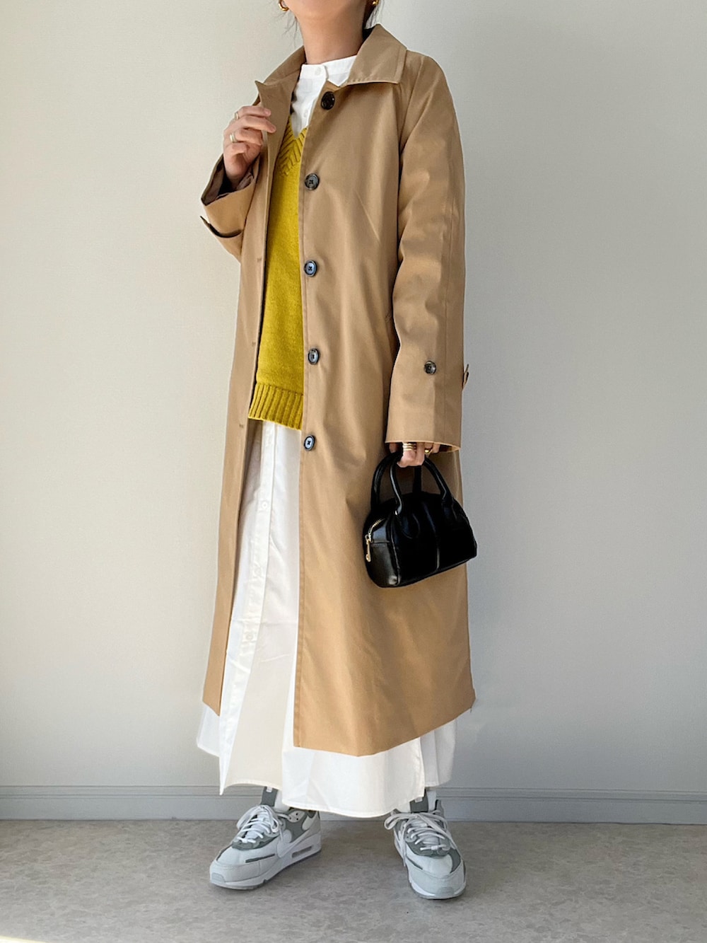 イエロー系のベスト、ホワイト系のシャツワンピース、ホワイト系のスニーカーを着用したレディースの冬コーディネートの2枚目の写真
