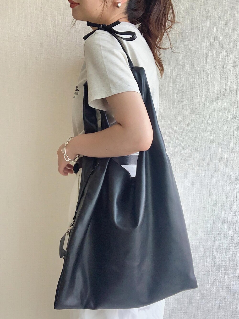 ベージュ系のTシャツ/カットソー、ブラック系のトートバッグ、グレー系のスニーカーを着用したレディースの夏コーディネートの2枚目の写真