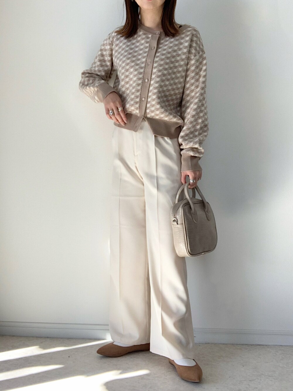 ベージュ系のカーディガン/ボレロ、ブラック系のTシャツ/カットソー、ホワイト系のデニムパンツを着用したレディースの冬コーディネートの3枚目の写真