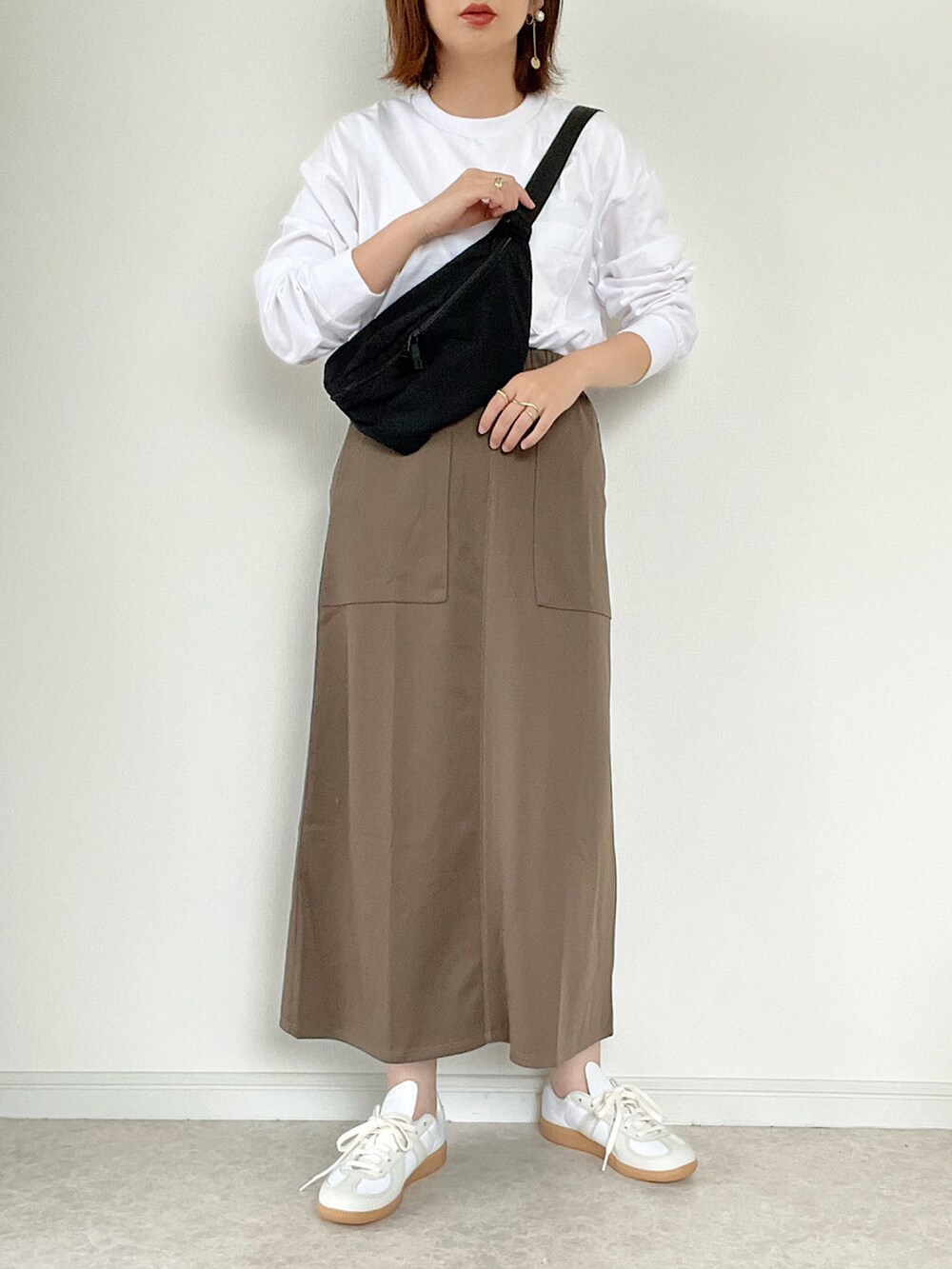 ブラック系のバッグ、ホワイト系のスニーカー、ブラウン系のカーディガン/ボレロを着用したレディースの夏コーディネートの2枚目の写真