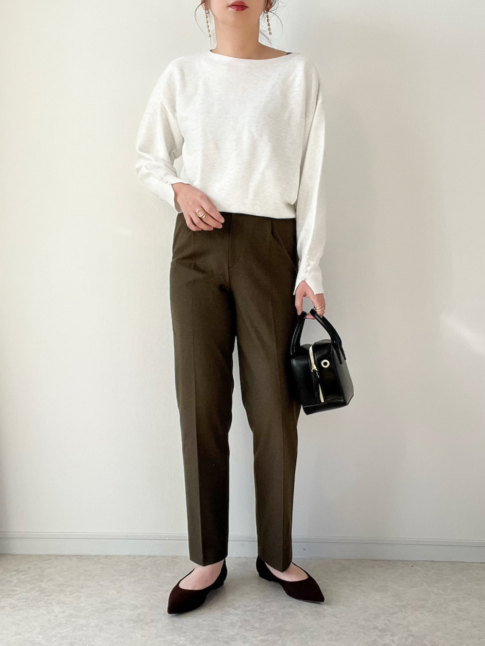 ホワイト系のニット/セーター、ブラウン系のパンツ、ブラック系のバッグを着用したレディースの冬コーディネートの2枚目の写真