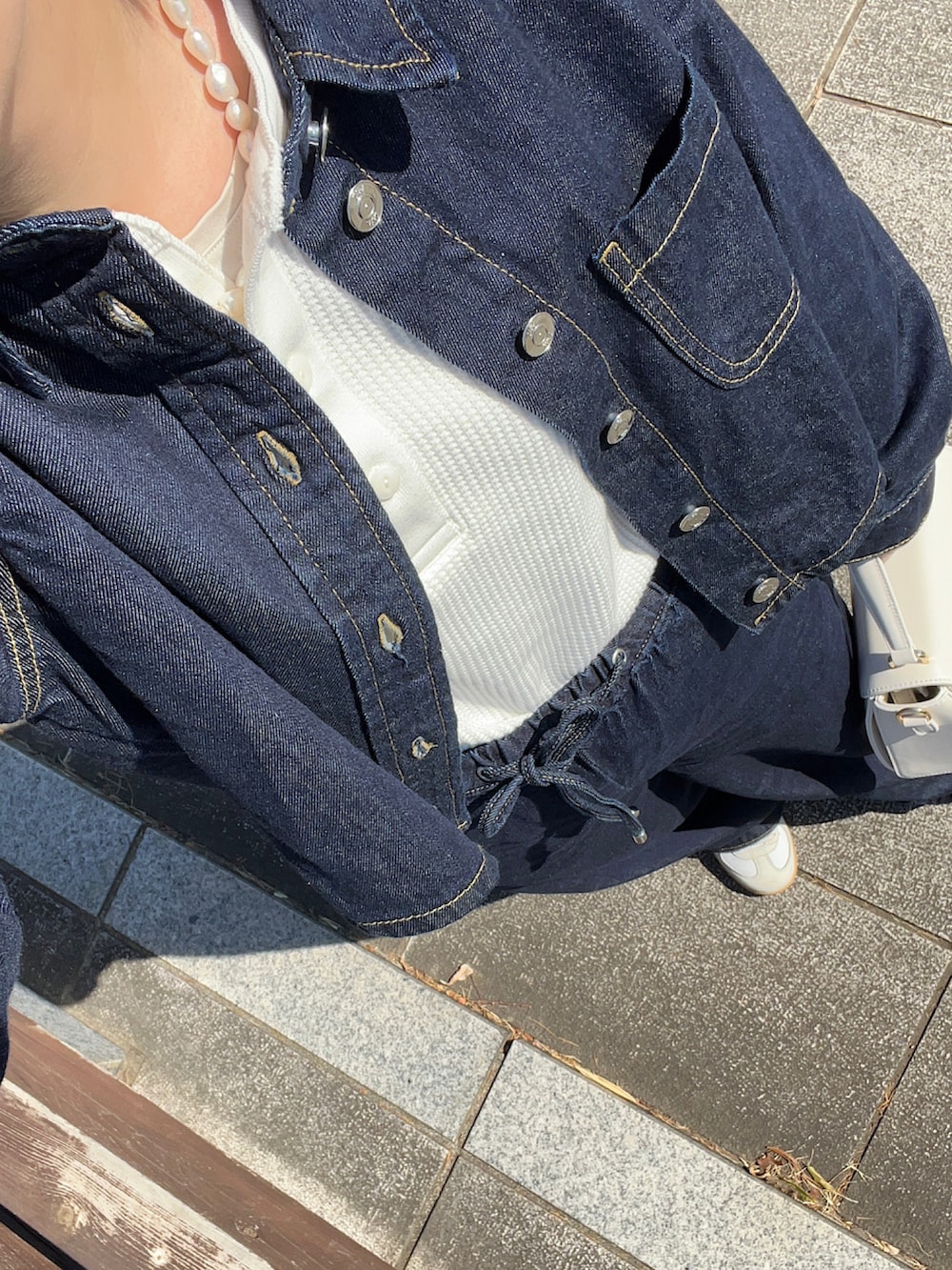 ホワイト系のショルダーバッグ、ホワイト系のスニーカー、ホワイト系のTシャツ/カットソーを着用したレディースの春コーディネートの2枚目の写真