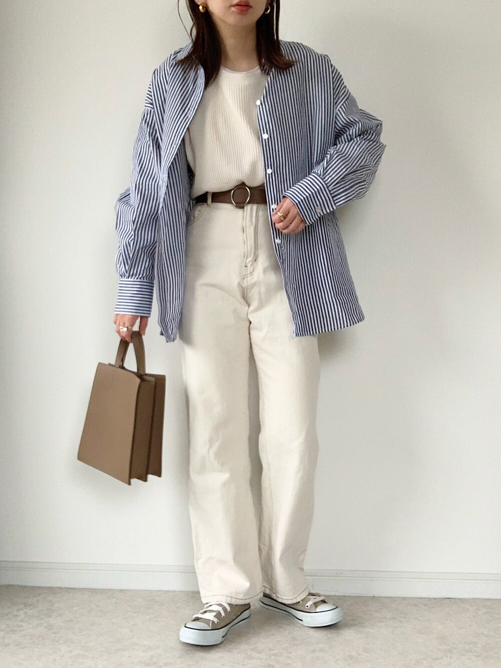 ホワイト系のTシャツ/カットソー、ブルー系のデニムパンツ、ブラック系のショルダーバッグを着用したレディースの春コーディネートの3枚目の写真