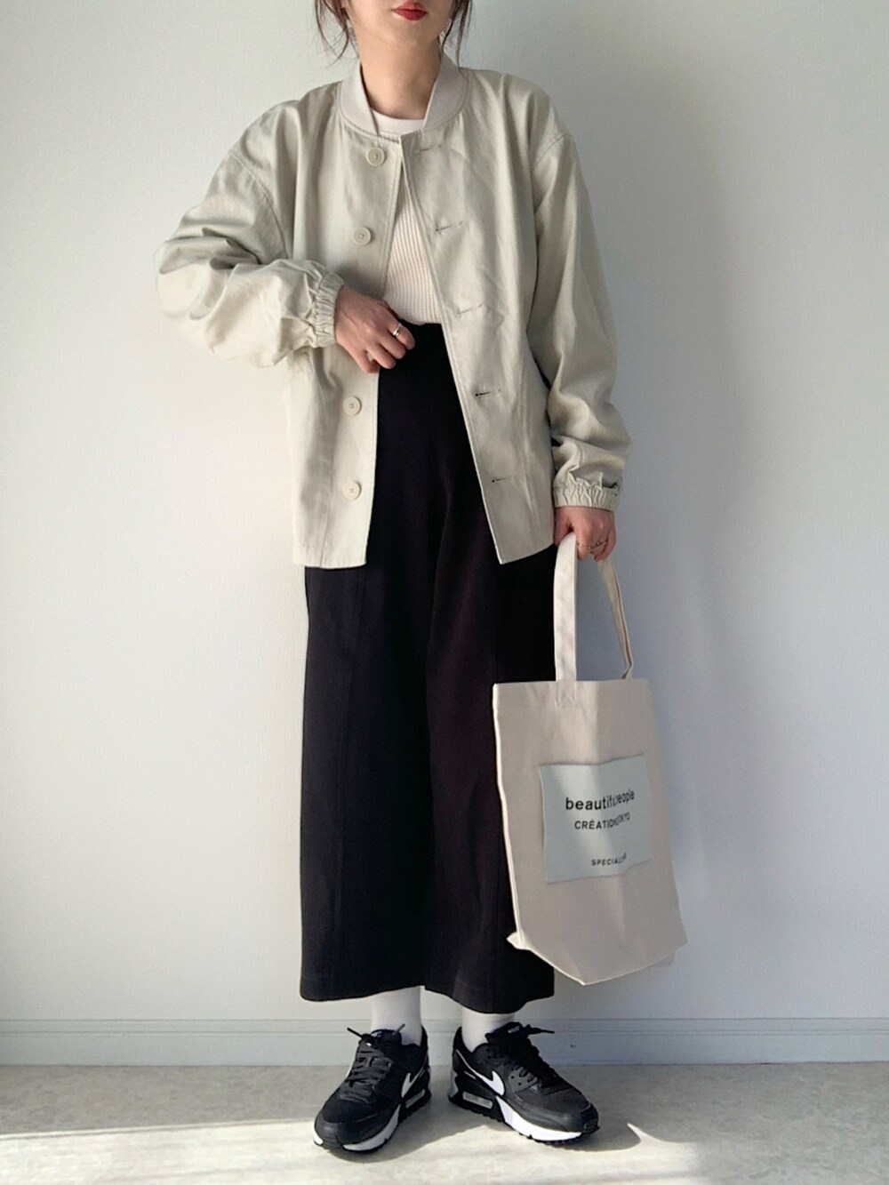 ホワイト系のTシャツ/カットソー、グレー系のニット/セーター、ブラック系のショルダーバッグを着用したレディースの冬コーディネートの5枚目の写真