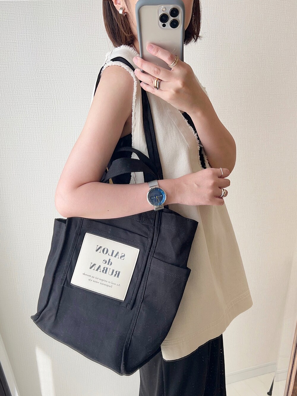 ホワイト系のベスト、ブラック系のトートバッグ、ブラック系のワンピースを着用したレディースの夏コーディネートの2枚目の写真