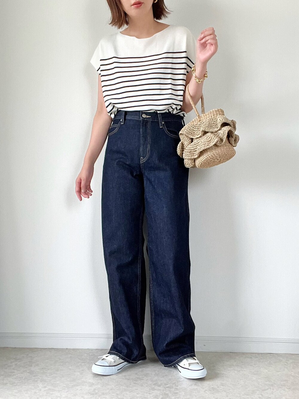 ベージュ系のベスト、ブルー系のデニムパンツ、ブラック系のショルダーバッグを着用したレディースの夏コーディネートの3枚目の写真