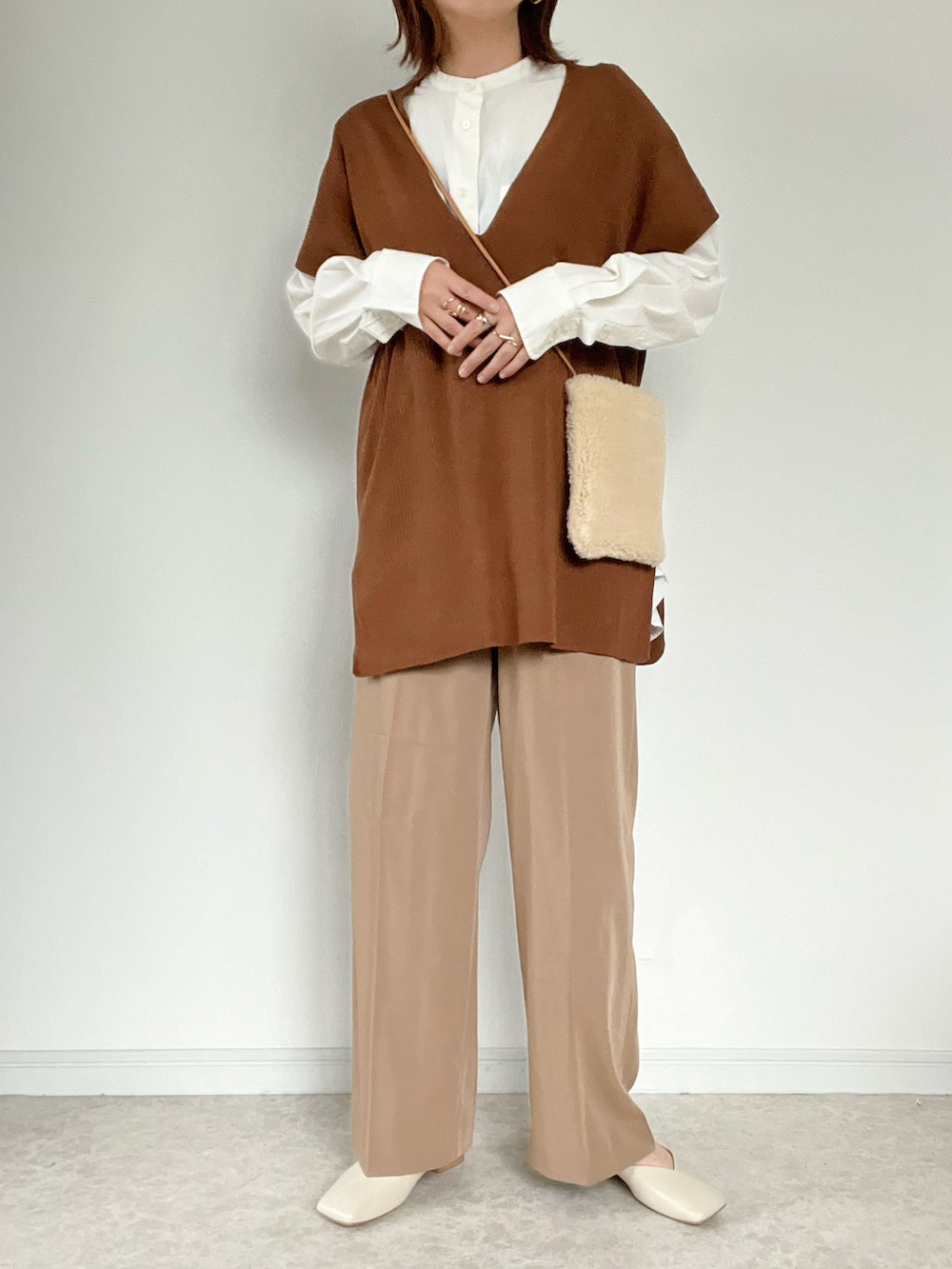 ブラウン系のベスト、ブラウン系のその他パンツ、ホワイト系のショルダーバッグを着用したレディースの秋コーディネートの2枚目の写真