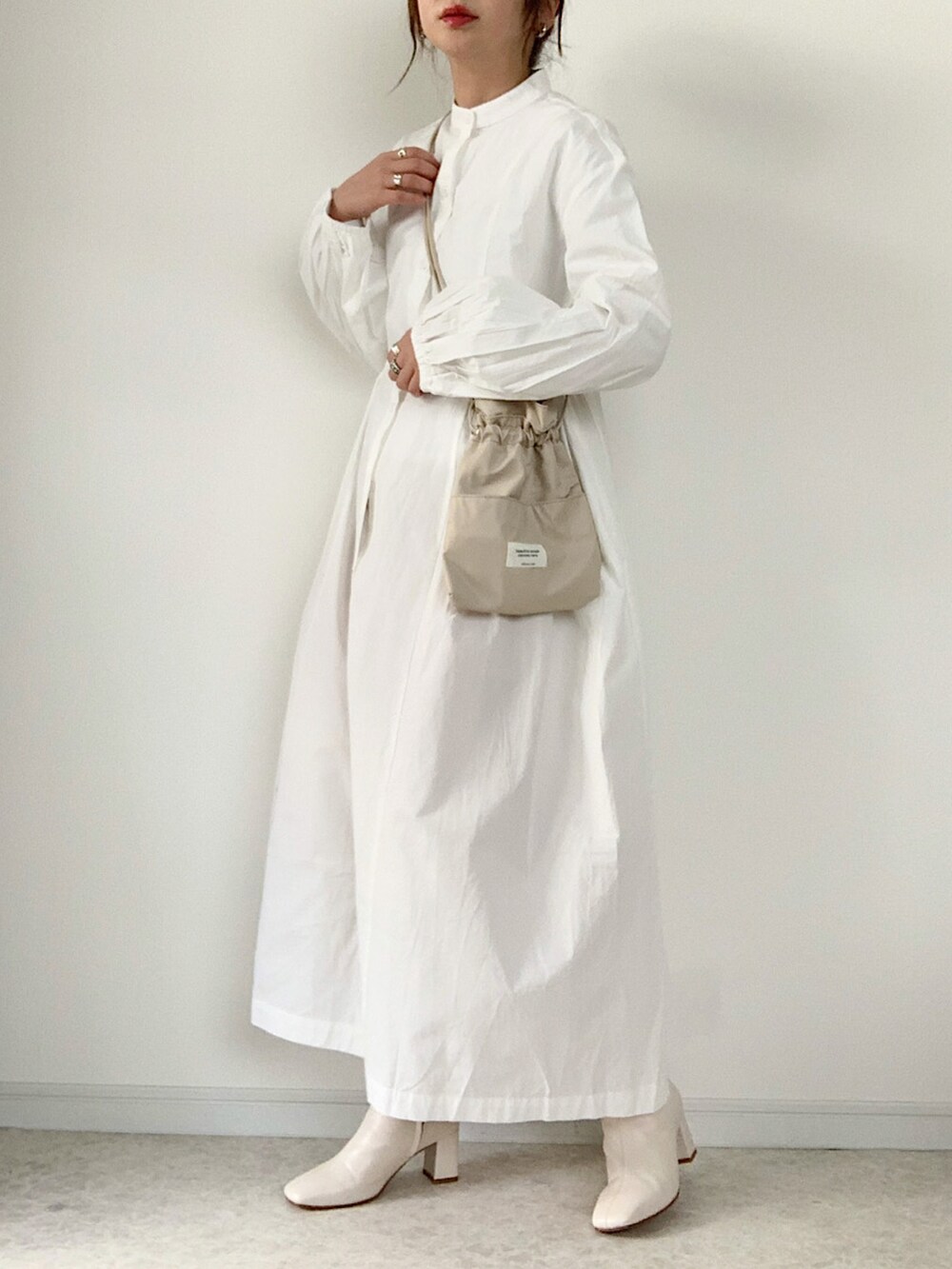 ブラック系のダウンベスト、ホワイト系のシャツワンピース、ベージュ系のショルダーバッグを着用したレディースの冬コーディネートの2枚目の写真