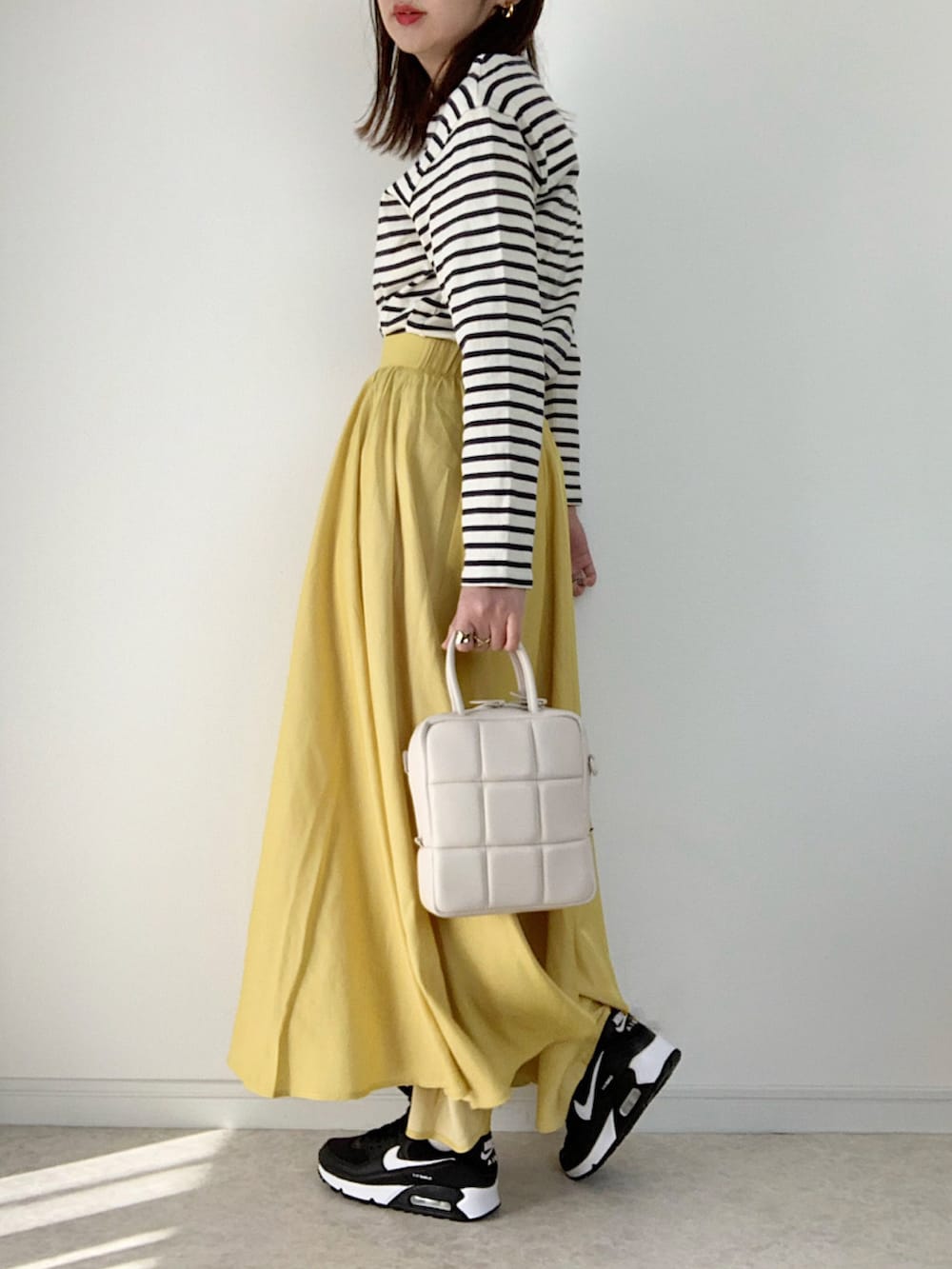 ホワイト系のニット/セーター、イエロー系のスカート、ブラック系のパンプスを着用したレディースの冬コーディネートの3枚目の写真