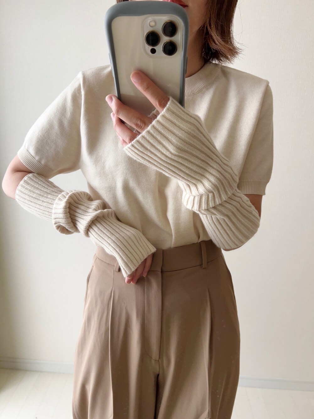 ホワイト系のニット/セーター、ベージュ系のパンツ、ブラウン系のショルダーバッグを着用したレディースの夏コーディネートの2枚目の写真