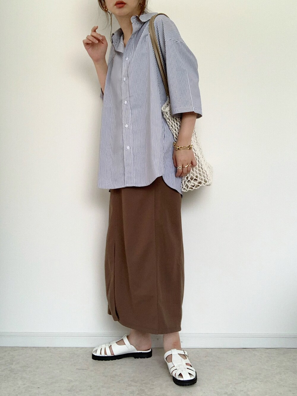 ブルー系のシャツ/ブラウス、ブラウン系のスラックス、ホワイト系のショルダーバッグを着用したレディースの夏コーディネートの2枚目の写真