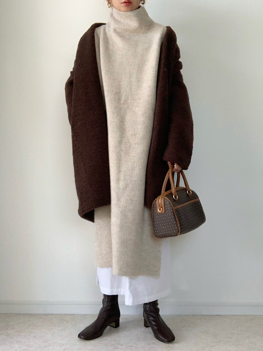 ホワイト系のニット/セーター、ブラウン系のブーツ、ブラウン系のノーカラーコートを着用したレディースの秋コーディネートの2枚目の写真
