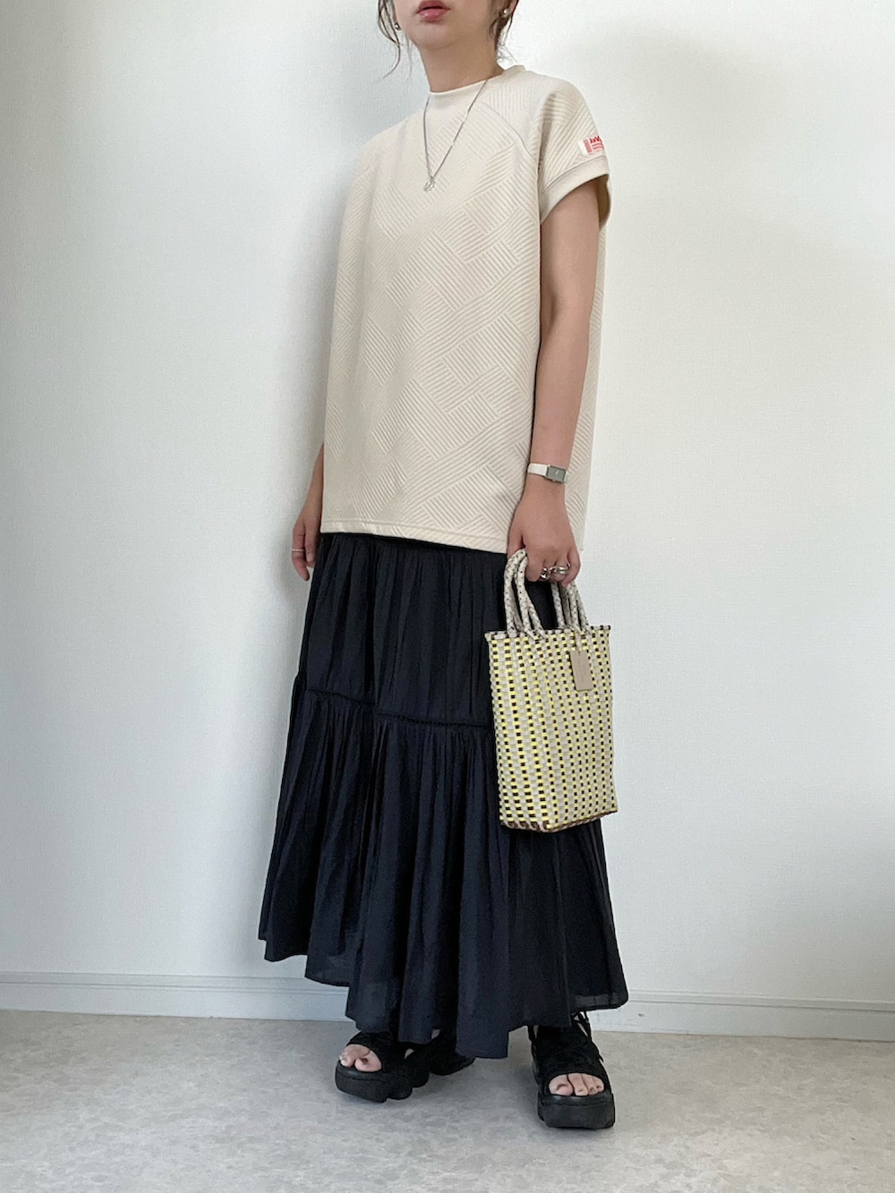 ベージュ系のTシャツ/カットソー、ベージュ系のスラックス、ブラウン系のハンドバッグを着用したレディースの夏コーディネートの4枚目の写真