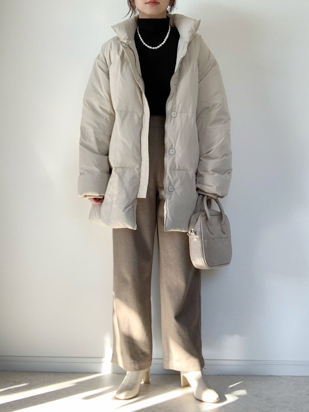 ベージュ系のダウンジャケット/コート、ホワイト系のTシャツ/カットソー、グレー系のスカートを着用したレディースの冬コーディネートの3枚目の写真
