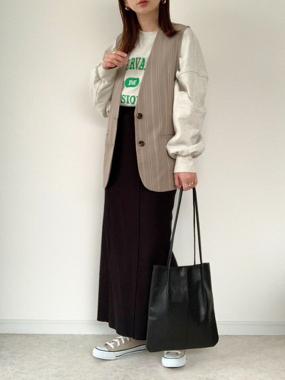 グリーン系のカーディガン/ボレロ、ブラック系のトートバッグ、ブラック系のスカートを着用したレディースの春コーディネートの4枚目の写真