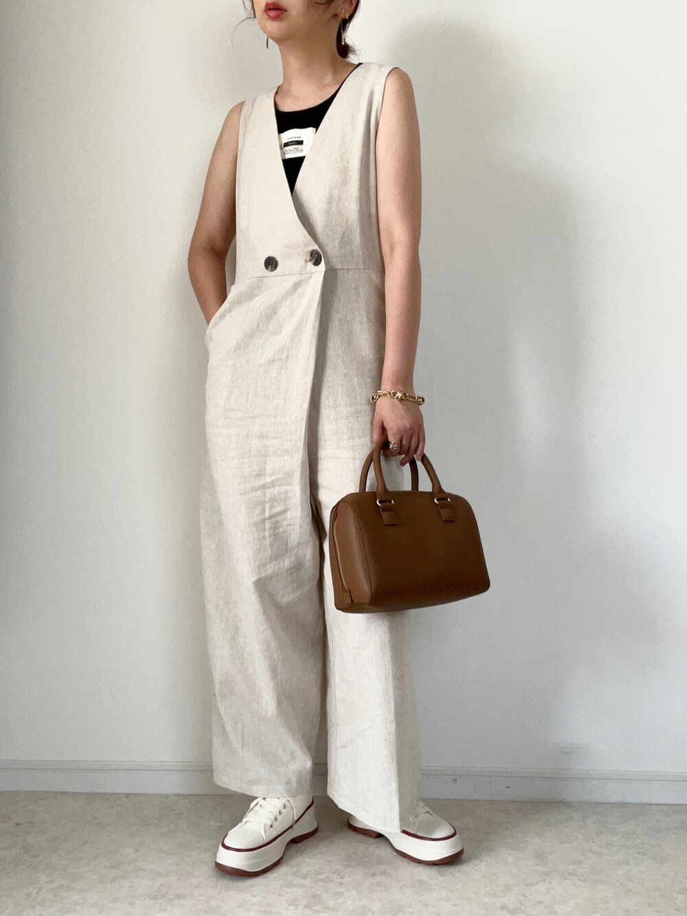 ホワイト系のサロペット/オーバーオール、ベージュ系のスニーカー、ブラウン系のハンドバッグを着用したレディースの夏コーディネートの2枚目の写真