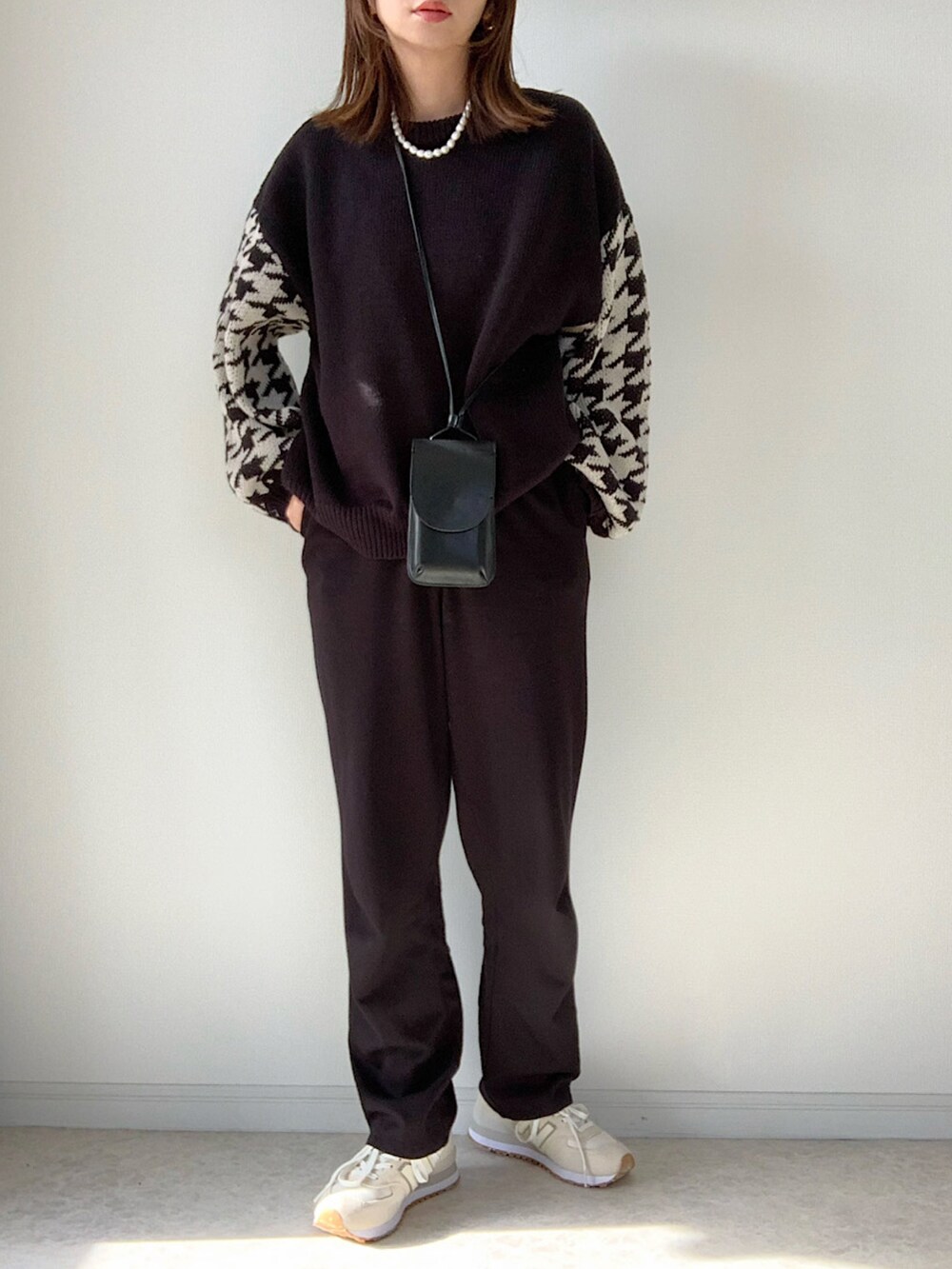 ブラック系のニット/セーター、ホワイト系のデニムパンツ、ホワイト系のスニーカーを着用したレディースの冬コーディネートの2枚目の写真