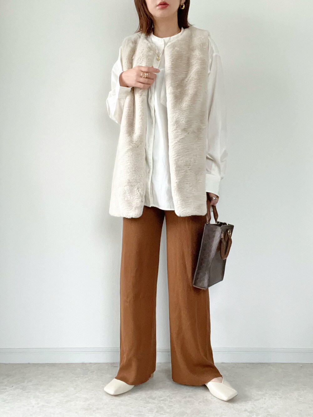 ブラウン系のベスト、ブラウン系のその他パンツ、ホワイト系のショルダーバッグを着用したレディースの秋コーディネートの3枚目の写真