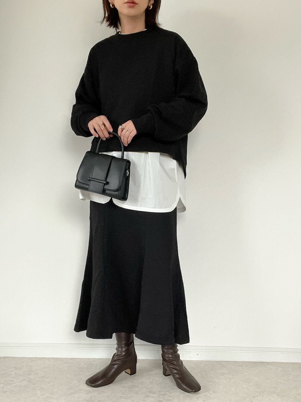 ブラック系のスウェット、ブラック系のスカート、グレー系のベストを着用したレディースの冬コーディネートの4枚目の写真