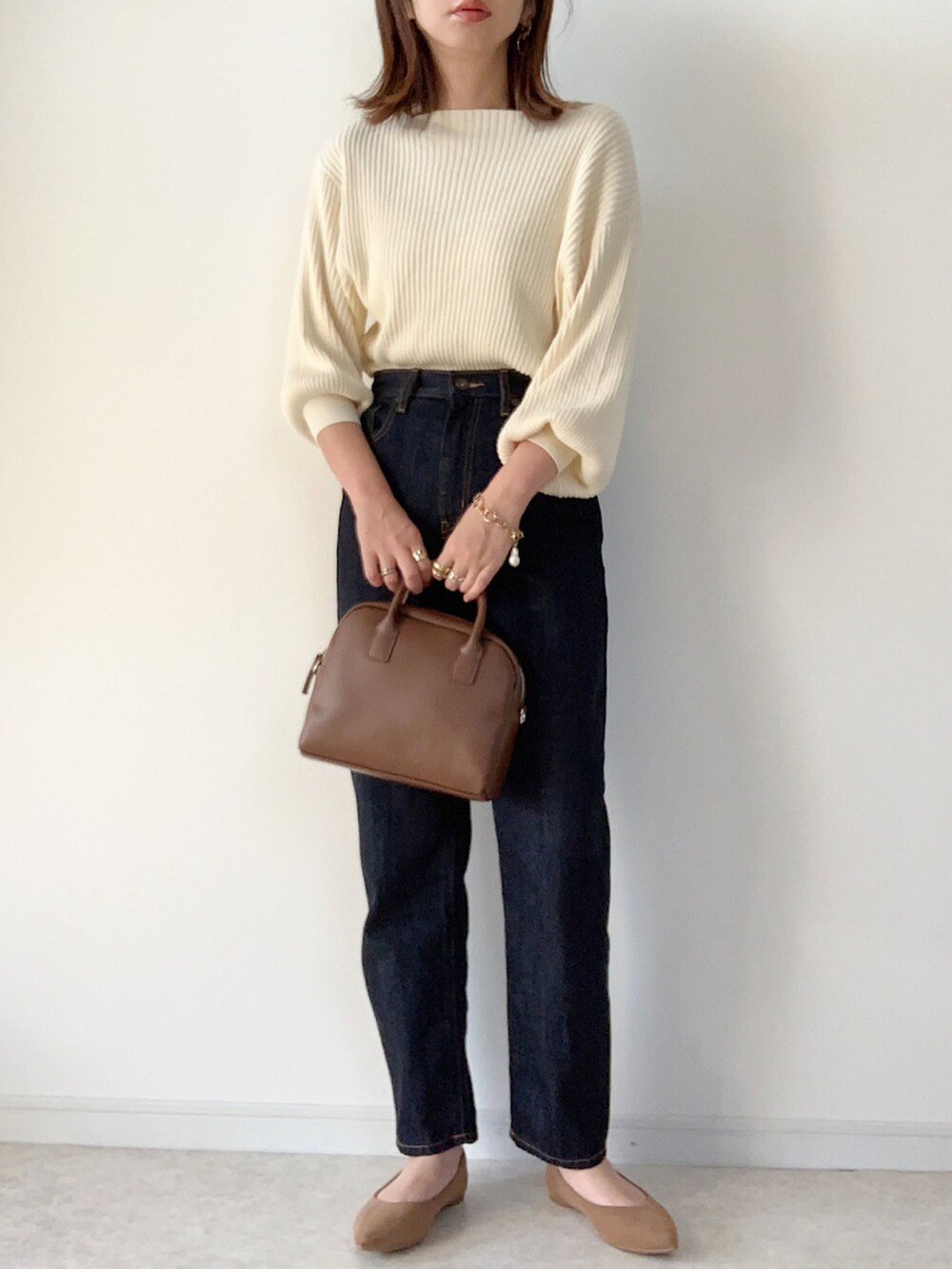 ホワイト系のニット/セーター、ベージュ系のその他パンツ、ブラウン系のバッグを着用したレディースの秋コーディネートの2枚目の写真